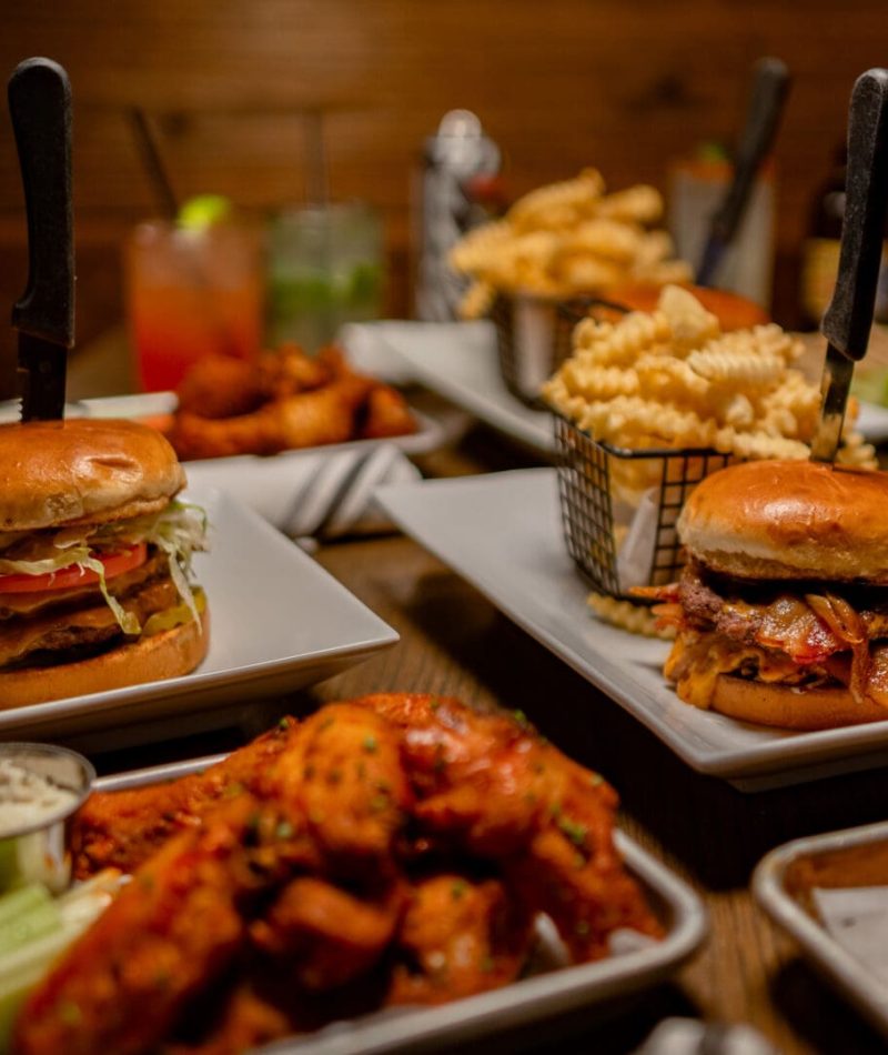 Bar Food Bacon cheeseburgers, chicken tenders, pizza, and crinkle fries at a bar restaurant.